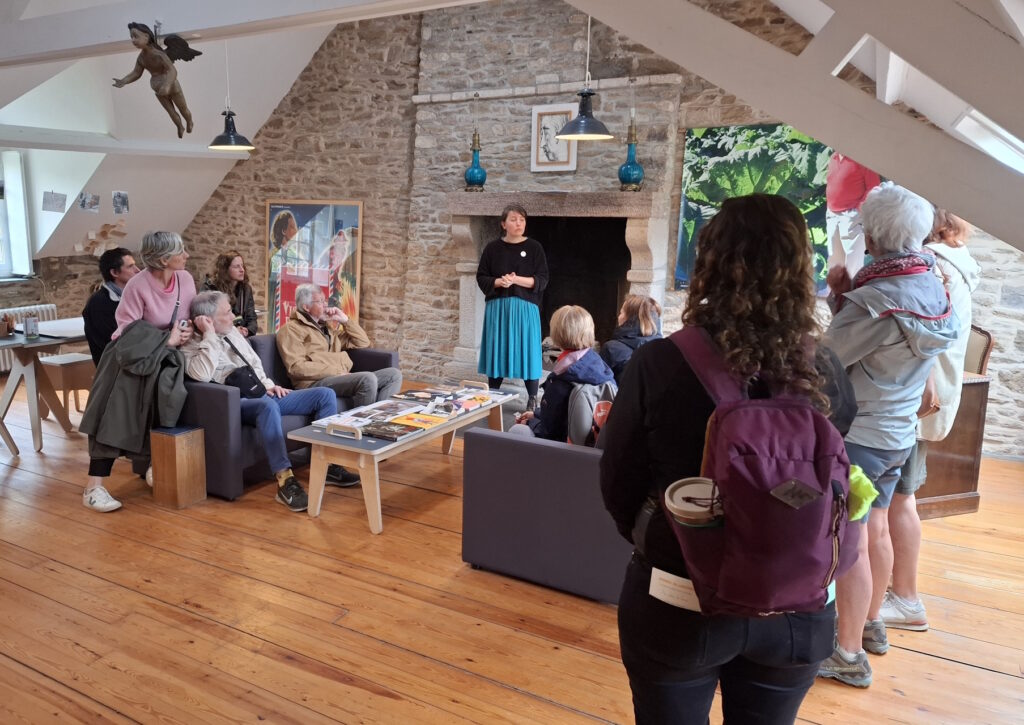 Des visiteurs écoutent une médiatrice leur parler de l'atelier de la maison lors d'une visite guidée.