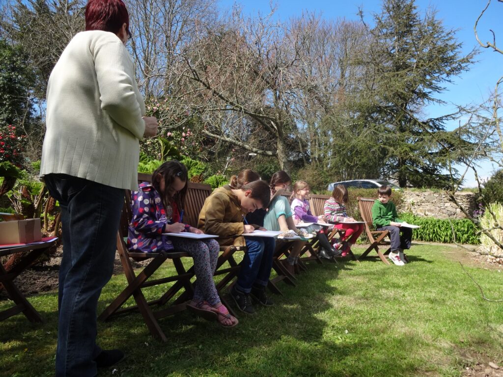 Des enfants dessinent dans le jardin de la maison Jacques Prévert
