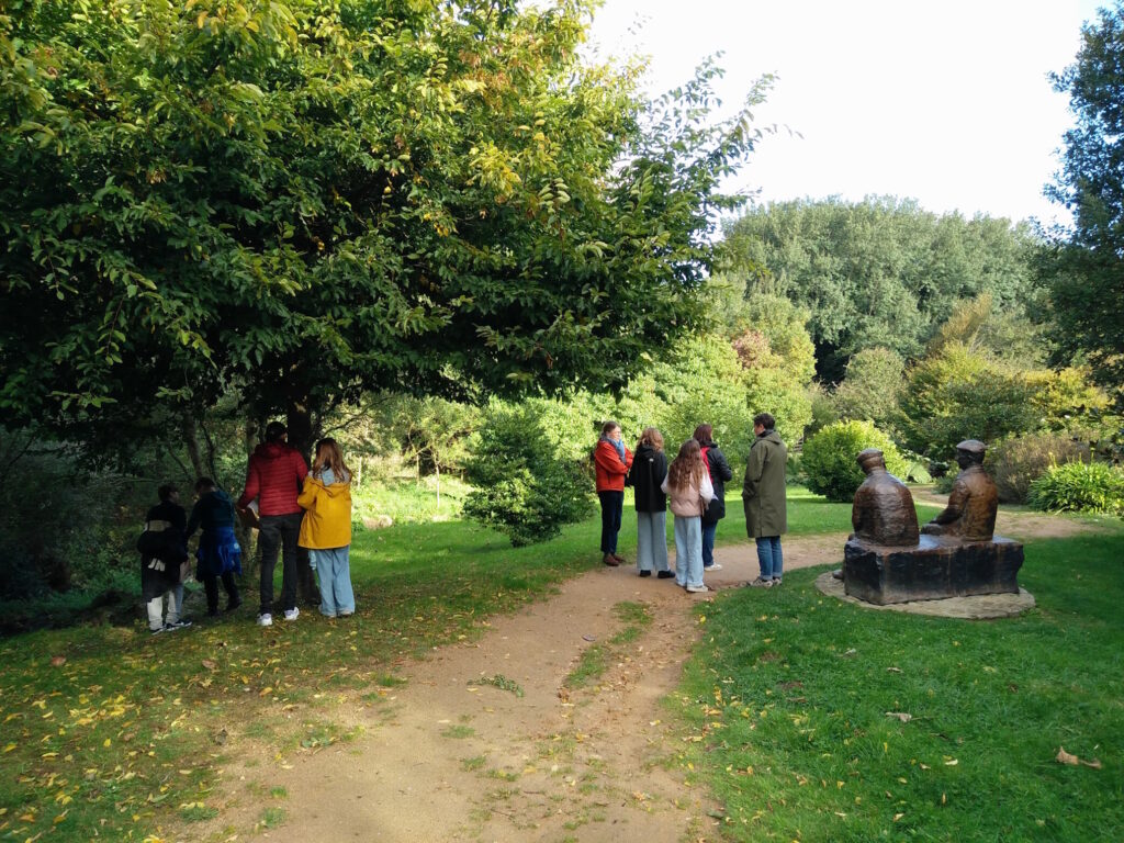 Les élèves font un jeu de chasse aux mots dans le parc communal d'Omonville-la-Petite, à côté de la statue représentant Jacques Prévert et Alexandre Trauner.