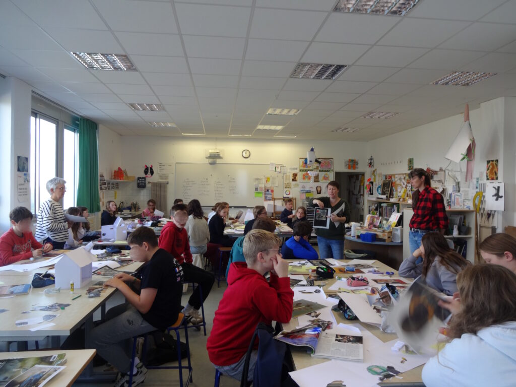 L'enseignante et Julie montrent des collages de Jacques Prévert aux élèves.