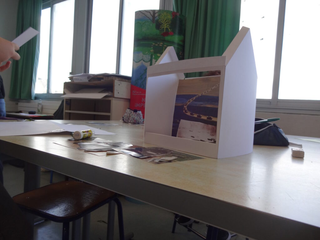 Un gros plan sur une maquette d'élève : complètement ouverte sur un côté, elle laisse voir le collage à l'intérieur.