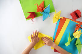 Deux mains sont en train de réaliser un oiseau en origami