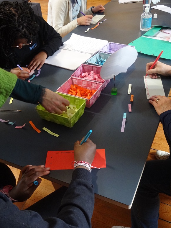 Des enfants et des adultes écrivent des phrases avec le jeu du Cadavre exquis