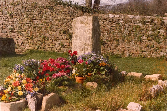 Stèle en granit avec à ses pieds des pots de fleurs.