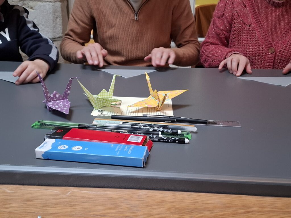 Des visiteurs réalisent une grue en origami.